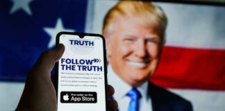 Smartphone displaying Truth Social app, Donald Trump background.