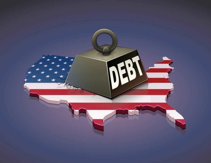 shutterstock_2100595465 A heavy weight labeled 'DEBT' sits on a map of the United States, symbolizing economic challenges.