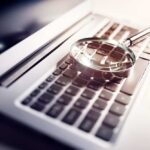 A magnifying glass resting on a laptop keyboard