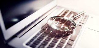 A magnifying glass resting on a laptop keyboard