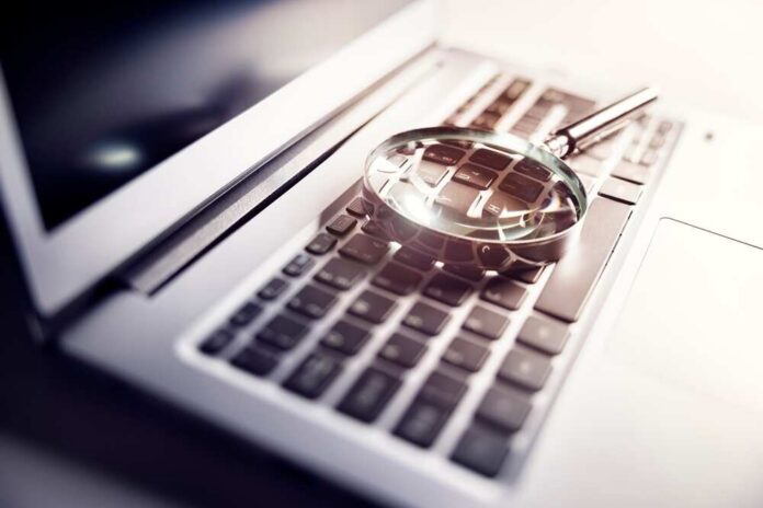 Magnifying,Glass,On,Laptop,Keyboard,Searc,For,Online,Documents,Background A magnifying glass resting on a laptop keyboard