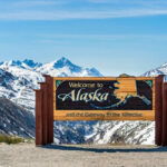 Alaska welcome sign with snowy mountains in background
