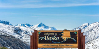 Alaska welcome sign with snowy mountains in background