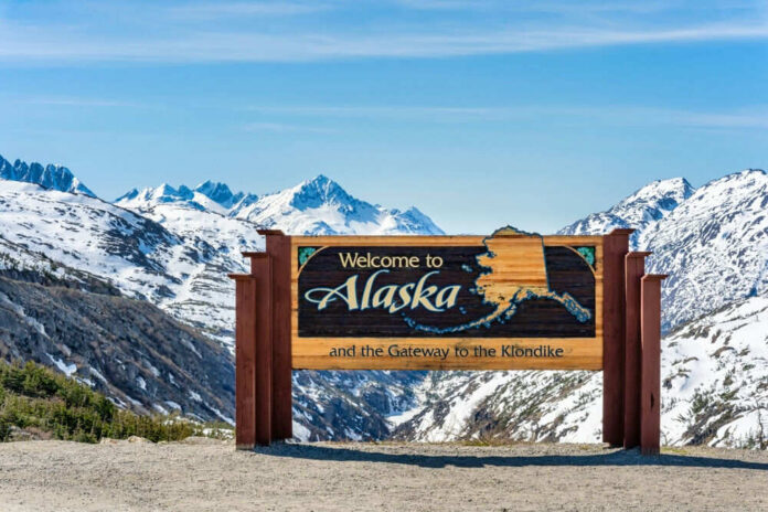 Alaska welcome sign with snowy mountains in background