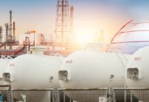 Trump Slams Big Oil’s War Jackpot Gas storage tanks in an industrial facility during sunrise