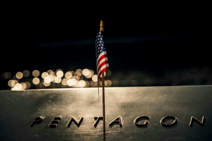 shutterstock_2321355077 American flag above engraved Pentagon sign at night