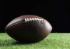 Football player kneeling on the field with a helmet beside them
