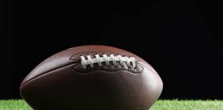 Football player kneeling on the field with a helmet beside them
