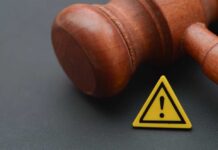 Shocking Court Admission Stuns Nation Wooden gavel with a yellow warning triangle sign on dark surface