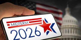 Hand holding a smartphone displaying 'MIDTERM 2026' with a star and American flag in the background