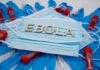 Ebola test tubes on lab table with gloved scientist in background