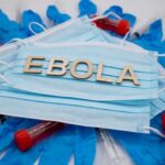 Ebola test tubes on lab table with gloved scientist in background