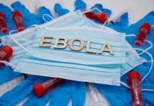 NEWS ALERT: Ebola Explosion Stuns World Ebola test tubes on lab table with gloved scientist in background