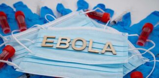 Ebola test tubes on lab table with gloved scientist in background