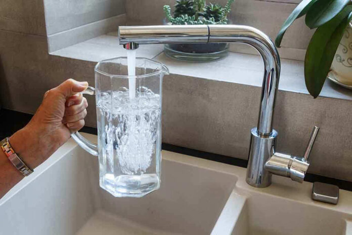 1450697639 Hand filling pitcher with water from faucet.