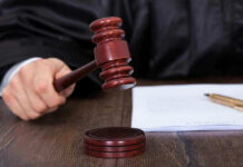 Parents Demand Death For Singer Judges hand holding gavel next to documents.