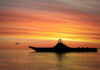 Silhouette of an aircraft carrier at sunset.