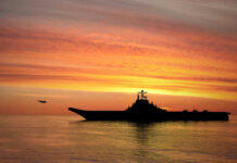 Silhouette of an aircraft carrier at sunset.