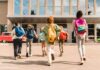 Group of schoolchildren with backpacks running toward a school entrance