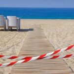 Tourists Trap Themselves Chasing ‘Epic’ Shot A wooden pathway leading to the beach with restricted access tape and chairs in the background