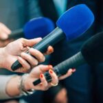 Bronx Mystery: Big Pussy’s Last Night Reporters holding colorful microphones