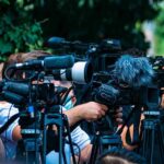 Defiant Power Play at Kennedy Center TV news cameras crowding together at an outdoor event
