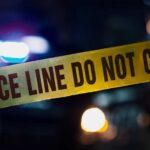 Midnight Hit Kills Sports Club Boss Police tape with blurred emergency lights in the background
