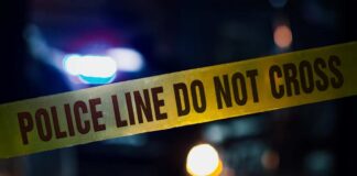 Police tape with blurred emergency lights in the background