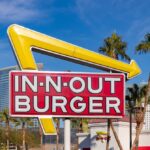 In-N-Out Burger sign with yellow arrow in city setting