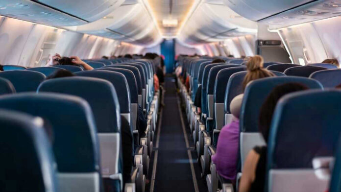 shutterstock_2292032849 Airplane interior with passengers seated mid-flight.