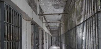 Empty prison corridor with barred cells on either side