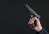 Warning Signs Ignored — Then Deadly Gunfire Hand holding a black semi-automatic pistol against a dark background