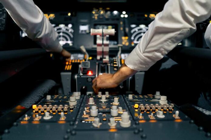 Pilots operate controls in an airplane cockpit