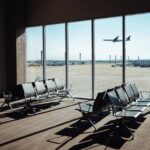 View of an airport waiting area with an airplane taking off in the background