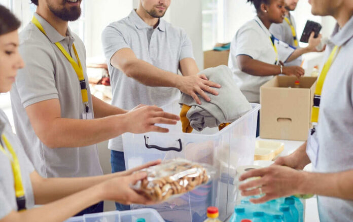 shutterstock_2482241741 People packing clothes and food into donation boxes