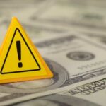 Fraud Money Supercharged A Media Empire A yellow warning sign placed on a pile of dollar bills