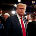 URGENT: 1,000 Missiles Locked On Iran Donald Trump in a navy suit with red tie at an event with cameras and crowd
