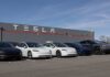 Tesla’s Makes BIG Bet Before BIG Reveal A lineup of Tesla cars parked in front of a Tesla building