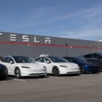 Tesla’s Makes BIG Bet Before BIG Reveal A lineup of Tesla cars parked in front of a Tesla building