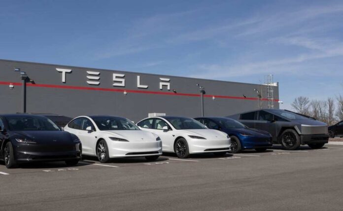 A lineup of Tesla cars parked in front of a Tesla building