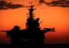 Aircraft carrier silhouette with jets at sunset