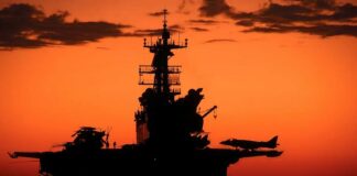 Aircraft carrier silhouette with jets at sunset