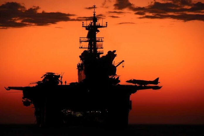 Aircraft carrier silhouette with jets at sunset
