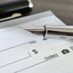 Record Paycheck Shock Close-up of a fountain pen poised over a blank check