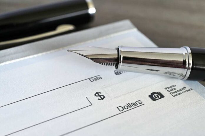 Fountain,Pen,On,A,Blank,Bank,Check,Cheque Close-up of a fountain pen poised over a blank check