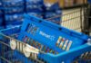 Retail War Erupts: Walmart Ambushes Amazon Blue shopping basket in a cart at a supermarket aisle