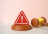 Infamous Murder Case: Judge On The Line A red warning sign next to a legal gavel on a light background