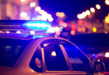 Lib City Bloodbath: Toddler Caught In Crossfire Police car with flashing blue lights at night.