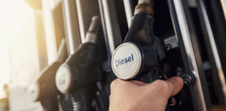 A hand holding a diesel fuel nozzle at a gas station