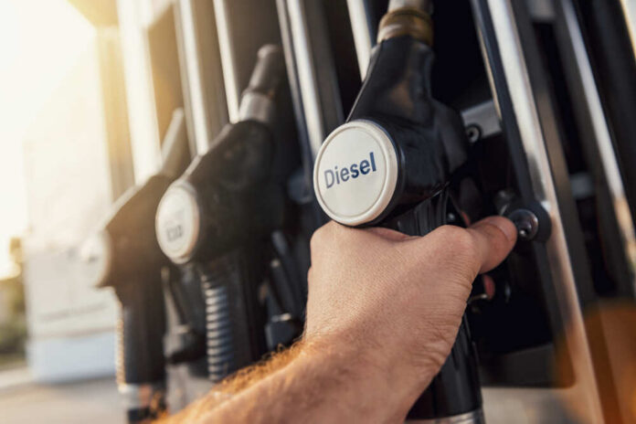 Man,Hand,Holding,Gas,Pump,Nozzle A hand holding a diesel fuel nozzle at a gas station